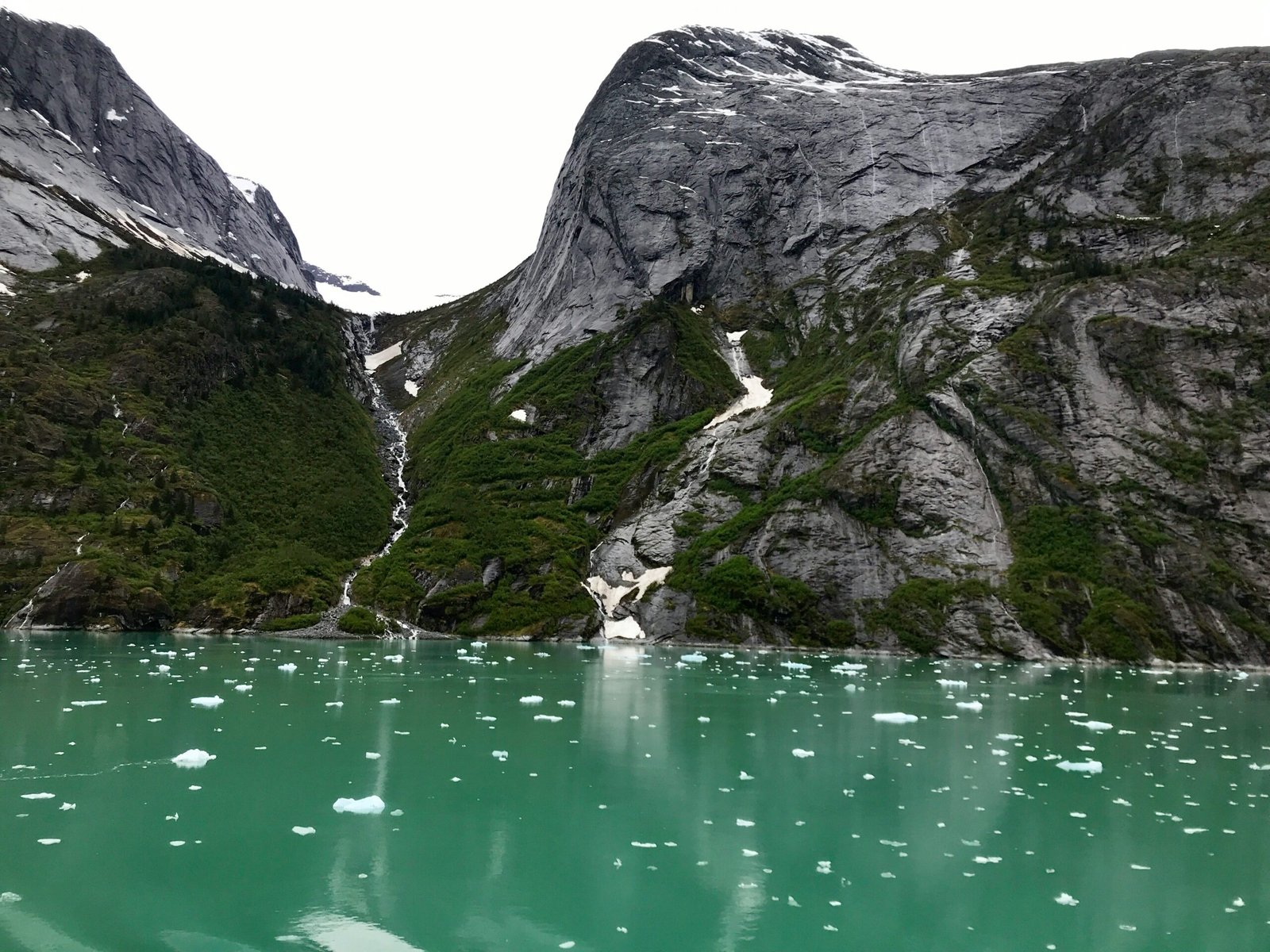 gray rocky mountain beside body of water during daytime